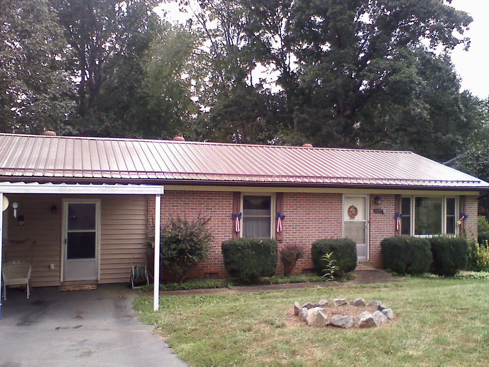 Bronze metal roof and carport on a brick ranch home — Roof Repair work by our crew in Rumford