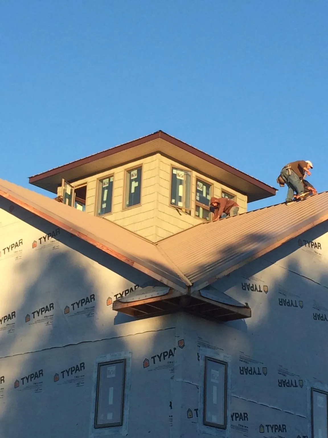 Roofers working around a rooftop cupola on a new metal roof at sunset — Roof Waterproofing in Rumford by Roofing Brothers